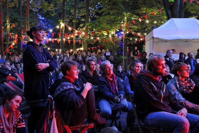 Viele Personen sitzen im Park auf Klappstühlen.