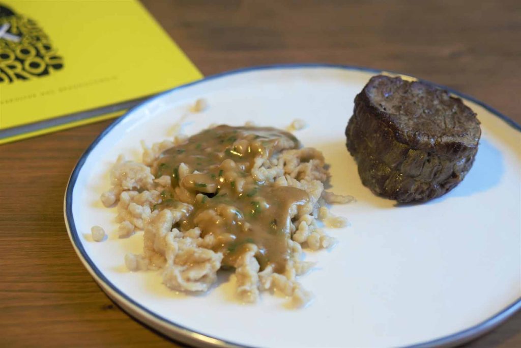 Teller mit Käsespätzle und Rindfleisch.