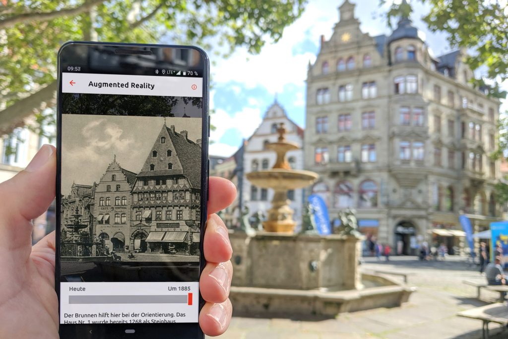 Ein Handy zeigt ein historisches Bild vom Kohlmarkt. In der rechten Bildhälfte ist der Kohlmarkt heute zu sehen. 