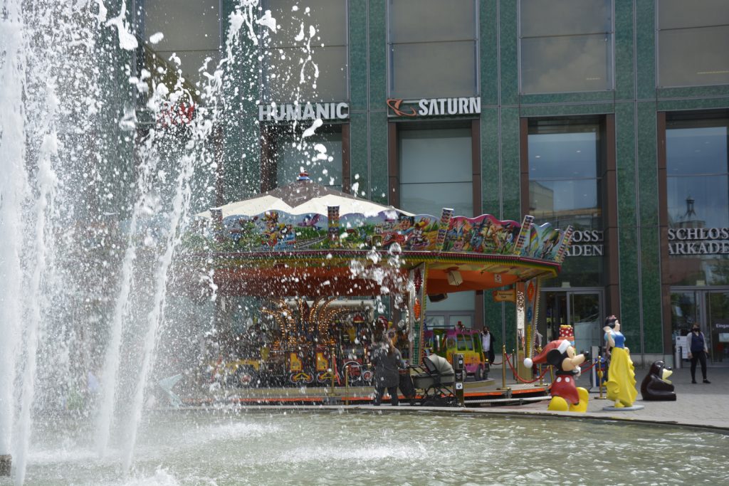 Im Vordergrund ist der Ritterbrunnen in Braunschweig zu sehen, dahinter ein Kinderkarussell.