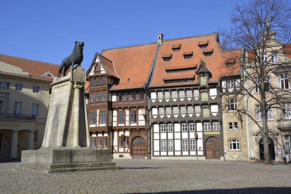 Historische Fachwerkfassade und Löwenstatue am Burgplatz.