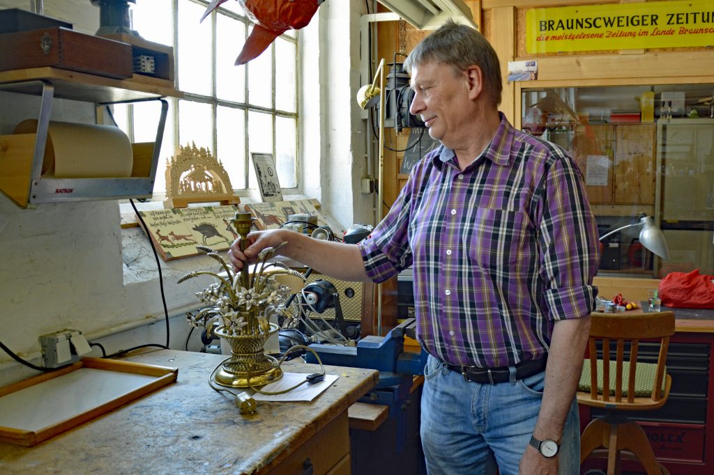 Ein Mann zeigt eine alte Lampe, die er repariert hat.